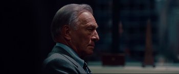 Movie still from “The Insider” (1999), directed by Michael Mann – An older man wearing a suit and tie looking to his left; Close Up shot, Over the shoulder angle