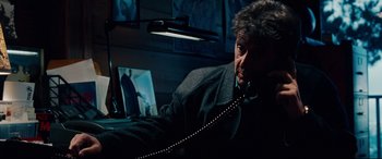Movie still from “The Insider” (1999), directed by Michael Mann – A man sitting in front of a lamp in a dark room; Close Up shot, Low angle