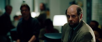 Movie still from “The Insider” (1999), directed by Michael Mann – A man with a bald head sitting in a room; Close Up shot, Over the shoulder angle