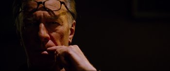 Movie still from “The Insider” (1999), directed by Michael Mann – An older man wearing glasses is looking into the distance; Close Up shot, Over the shoulder angle