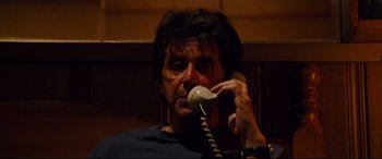 Movie still from “The Insider” (1999), directed by Michael Mann – A man talking on a phone in a dark room; Close Up shot, Low angle