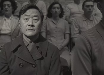 Movie still from “Asteroid City” (2023), directed by Wes Anderson – An old photo of a group of people sitting in a room; Medium shot, Low angle
