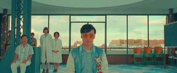 Movie still from “Asteroid City” (2023), directed by Wes Anderson – A man and a woman standing in front of a window; Medium shot, Low angle