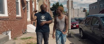 Two men standing on the side of the road talking to each other