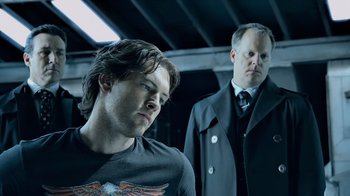 Movie still from “Avatar” (2009), directed by James Cameron – Two men standing next to each other in front of a building; Medium shot, Low angle