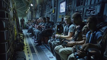 Movie still from “Avatar” (2009), directed by James Cameron – A group of men sitting on a plane in the middle of the day; Wide shot, High angle