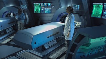 Movie still from “Avatar” (2009), directed by James Cameron – A person standing in front of an mri machine in a room; Wide shot, High angle