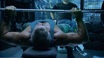 Movie still from “Avatar” (2009), directed by James Cameron – A man is lifting a barbell in a gym; Medium shot, Low angle