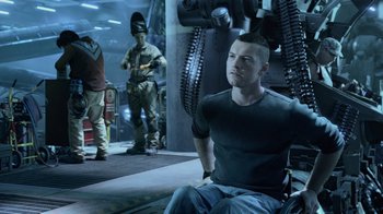 Movie still from “Avatar” (2009), directed by James Cameron – A man sitting on a chair in front of a machine; Medium shot, Over the shoulder angle