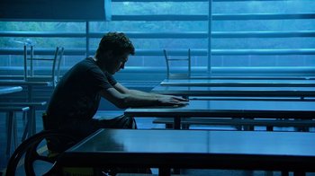 Movie still from “Avatar” (2009), directed by James Cameron – A man sitting at a table looking at his cell phone; Wide shot, High angle
