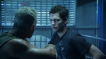 Movie still from “Avatar” (2009), directed by James Cameron – A man is looking at another man in a dark room; Close Up shot, Over the shoulder angle