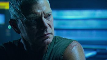 Movie still from “Avatar” (2009), directed by James Cameron – An older man looking into the distance in a dark room; Close Up shot, Over the shoulder angle