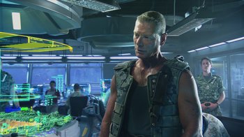 Movie still from “Avatar” (2009), directed by James Cameron – A man in a vest standing in front of computer screens; Medium shot, Low angle