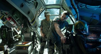 Movie still from “Avatar: The Way of Water” (2022), directed by James Cameron – Two men in fatigues working inside a helicopter; Medium shot, High angle