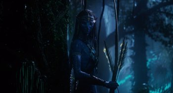 Movie still from “Avatar: The Way of Water” (2022), directed by James Cameron – A woman dressed as neytiri from avatar holding a bow and arrow; Wide shot, Over the shoulder angle