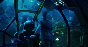 Movie still from “Avatar: The Way of Water” (2022), directed by James Cameron – A man standing inside of an underwater submarine; Wide shot, Over the shoulder angle