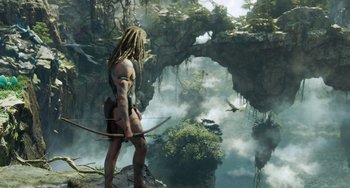 Movie still from “Avatar: The Way of Water” (2022), directed by James Cameron – A man standing on top of a mountain holding a bow; Wide shot, Low angle