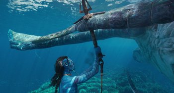 Movie still from “Avatar: The Way of Water” (2022), directed by James Cameron – An underwater photo of a man holding a pole; Wide shot, Overhead angle