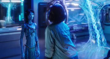 Movie still from “Avatar: The Way of Water” (2022), directed by James Cameron – A woman is standing in front of another woman in a blue room; Medium shot, Over the shoulder angle