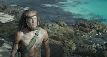 Movie still from “Avatar: The Way of Water” (2022), directed by James Cameron – A man in a body suit standing next to a body of water; Medium shot, Overhead angle