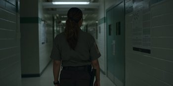 Movie still from “Awake” (2021), directed by Mark Raso – A woman in uniform walking down a hall way; Medium shot, Over the shoulder angle