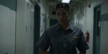 Movie still from “Awake” (2021), directed by Mark Raso – A woman standing in a hallway with her arms crossed; Medium shot, Low angle