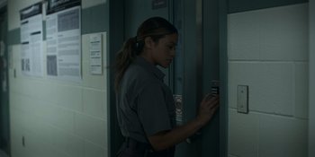 Movie still from “Awake” (2021), directed by Mark Raso – A woman in a gray shirt is looking at her cell phone; Medium shot, Low angle