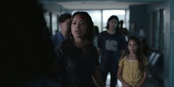 Movie still from “Awake” (2021), directed by Mark Raso – A group of people standing in a room; Medium shot, Over the shoulder angle