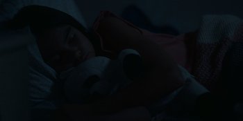 Movie still from “Awake” (2021), directed by Mark Raso – A woman sleeping in a bed with a teddy bear; Close Up shot, High angle