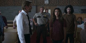 Movie still from “Awake” (2021), directed by Mark Raso – A group of people standing in front of a building; Medium shot, Over the shoulder angle