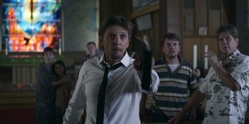 Movie still from “Awake” (2021), directed by Mark Raso – A man in a white dress shirt and black tie holding a knife in his hand; Medium shot, Low angle