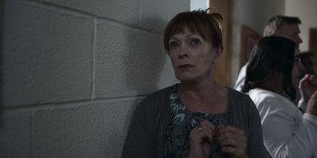 Movie still from “Awake” (2021), directed by Mark Raso – A woman standing next to a brick wall looking up; Close Up shot, Low angle