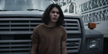 Movie still from “Awake” (2021), directed by Mark Raso – A young man standing in front of a parked truck; Close Up shot, Low angle