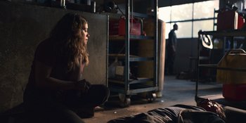 Movie still from “Awake” (2021), directed by Mark Raso – A woman sitting on the ground in a room; Medium shot, Over the shoulder angle