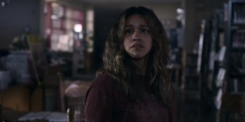 Movie still from “Awake” (2021), directed by Mark Raso – A young woman with long brown hair stares into the camera; Close Up shot, Over the shoulder angle