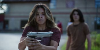 Movie still from “Awake” (2021), directed by Mark Raso – A woman holding a gun in her hands; Medium shot, Low angle