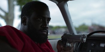 Movie still from “Awake” (2021), directed by Mark Raso – A man holding a gun while sitting in a car; Close Up shot, Over the shoulder angle