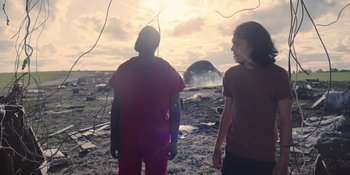 Movie still from “Awake” (2021), directed by Mark Raso – Two people standing on a beach looking at a deflated balloon; Medium shot, Low angle