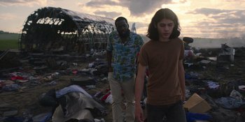 Movie still from “Awake” (2021), directed by Mark Raso – Two men walking through a pile of trash; Medium shot, Low angle