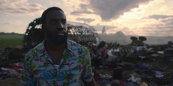 Movie still from “Awake” (2021), directed by Mark Raso – A man standing in front of a pile of trash; Medium shot, Low angle