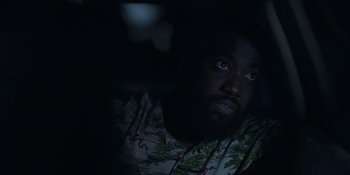 Movie still from “Awake” (2021), directed by Mark Raso – A man with a beard is sitting in the dark; Close Up shot, High angle