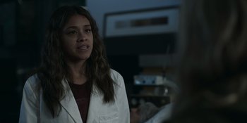 Movie still from “Awake” (2021), directed by Mark Raso – A woman in a white lab coat looking at a camera; Close Up shot, Over the shoulder angle