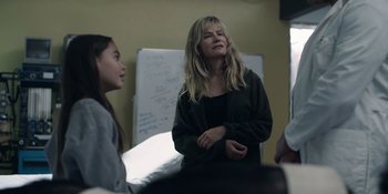 Movie still from “Awake” (2021), directed by Mark Raso – A woman standing next to another woman in a room; Medium shot, Over the shoulder angle