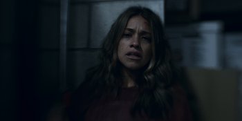 Movie still from “Awake” (2021), directed by Mark Raso – A woman with long brown hair is crying in a dark room; Close Up shot, Over the shoulder angle