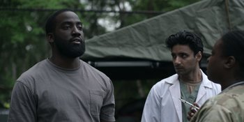 Movie still from “Awake” (2021), directed by Mark Raso – Two men standing next to each other in a forest; Medium shot, Over the shoulder angle