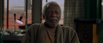 Movie still from “Baby Driver” (2017), directed by Edgar Wright – An older man wearing a robe and smiling for the camera; Close Up shot, High angle