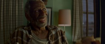 Movie still from “Baby Driver” (2017), directed by Edgar Wright – An older man smiling for the camera in a living room; Close Up shot, Low angle