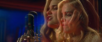 Movie still from “Baby Driver” (2017), directed by Edgar Wright – Two beautiful young women singing into microphones in front of microphones; Close Up shot, Low angle