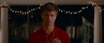 Movie still from “Baby Driver” (2017), directed by Edgar Wright – A young man wearing a red shirt is listening to music; Close Up shot, Over the shoulder angle