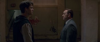 Movie still from “Baby Driver” (2017), directed by Edgar Wright – A man and a man standing next to each other in a room; Medium shot, Over the shoulder angle